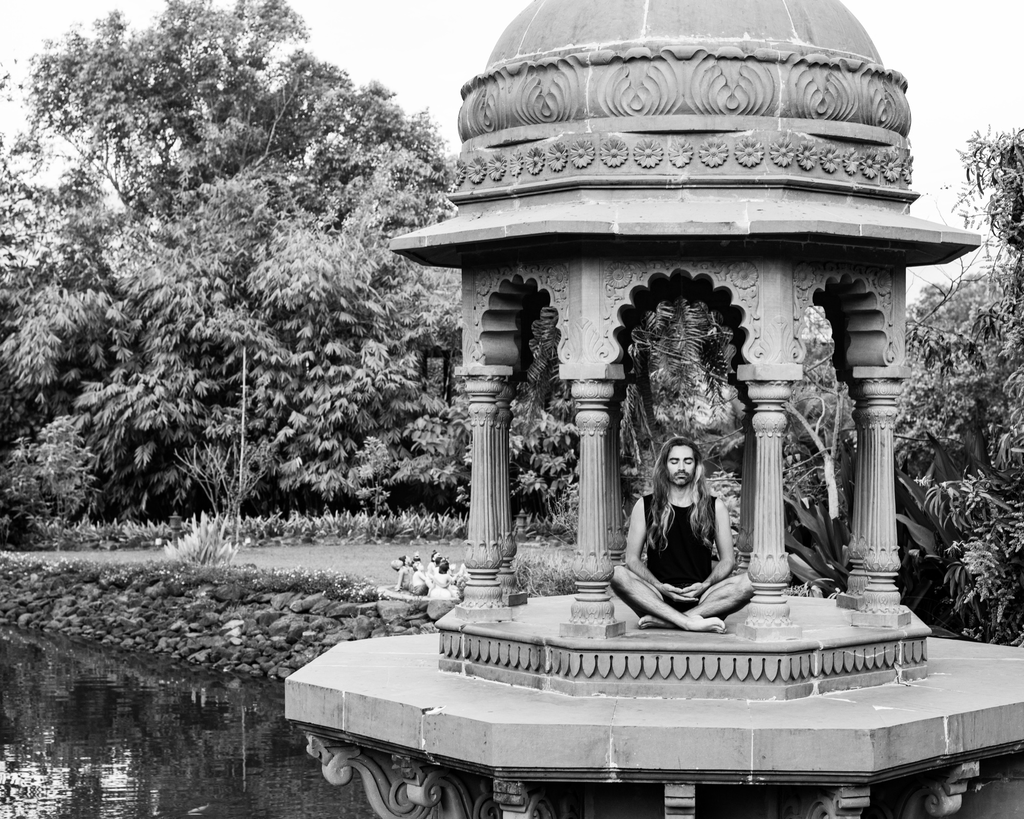 Jeremy seated cross-legged between carved stone columns in India. Black-and-white photograph by Richard Pilnick.